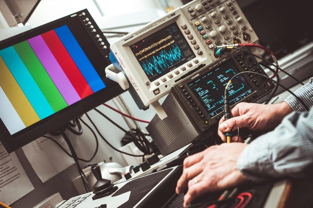 Techniker bedient elektronische Laborprüf- und Messgeräte mit Farbdisplay.